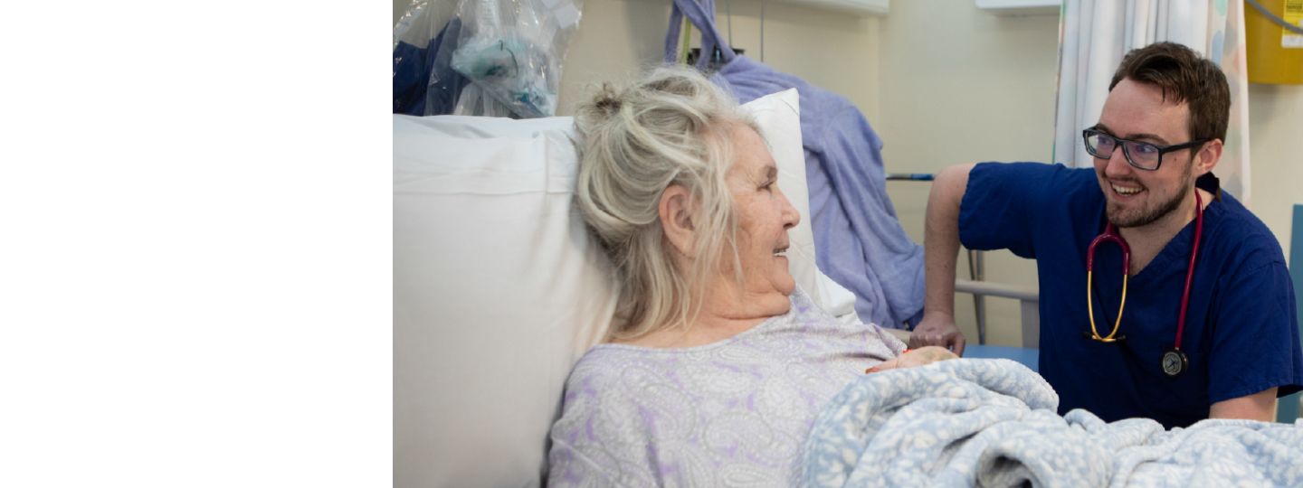 Older female patient in hospital bed and talking to male doctor